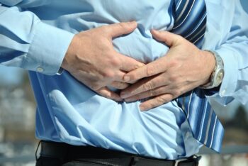Un bărbat în cămașă albastră care acuză dureri abdominale