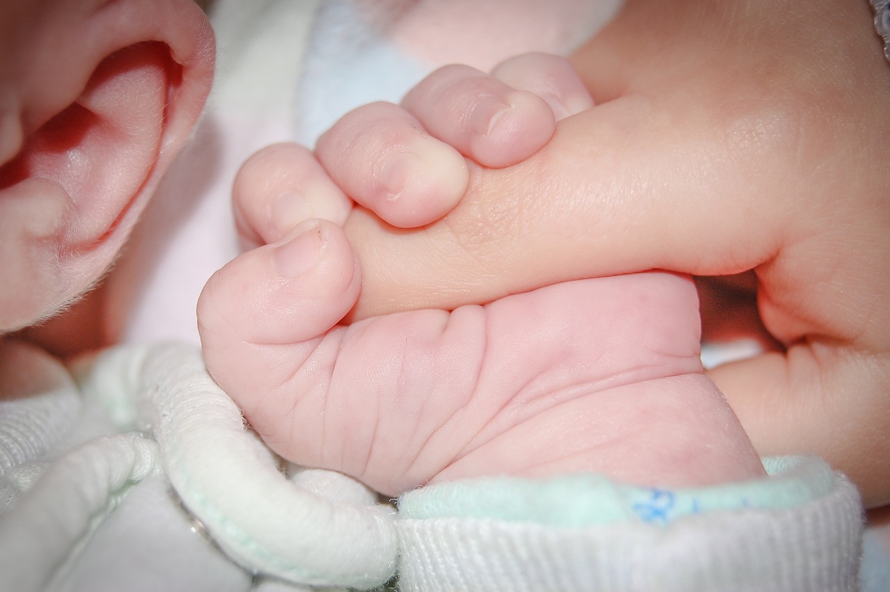 Bebeluș care își ține mama de mână