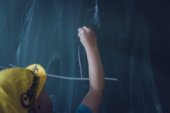 Copil care scrie pe o tablă